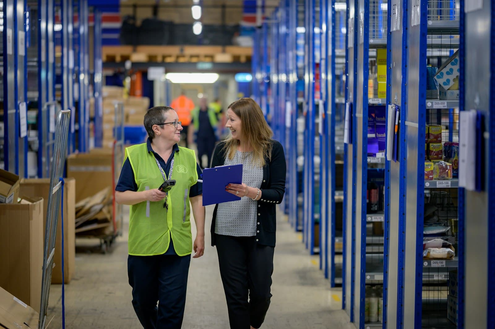 A supervisor reviewing an incident report on a clipboard in a warehouse aisle